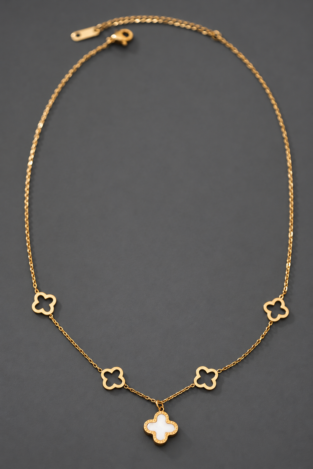 Collar de trébol reversible en acero inoxidable sobre fondo gris carbón