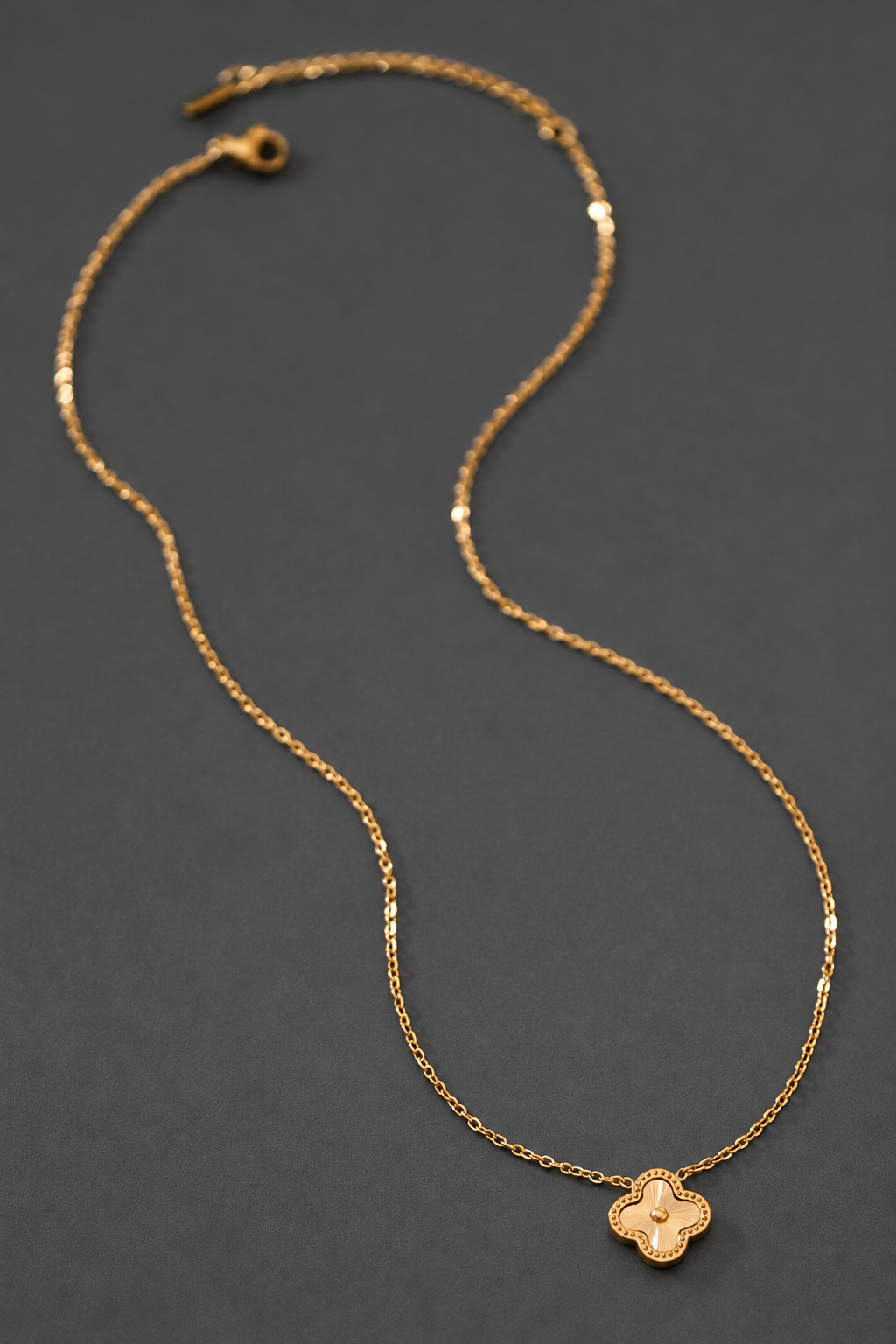Collar de trébol en acero inoxidable sobre fondo gris carbón