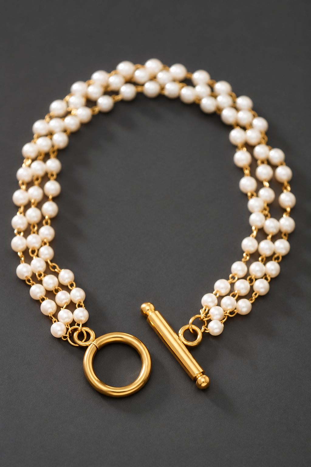 Pulsera de varias tiras con baño de oro de 18K sobre fondo gris carbón
