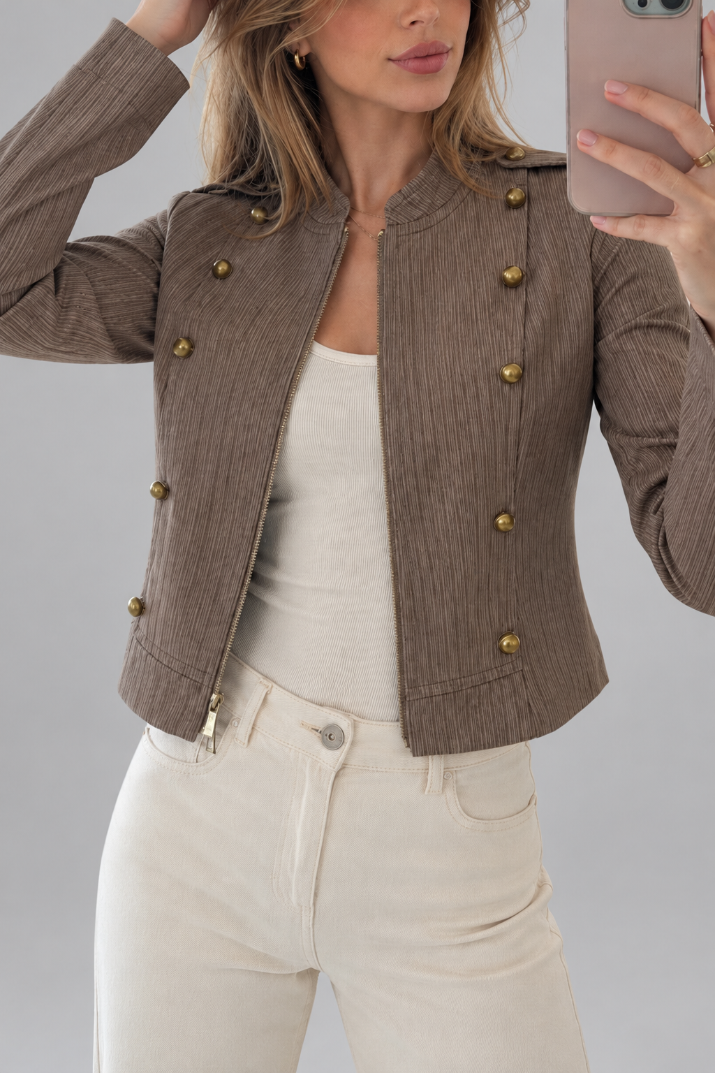 Chaqueta estilo militar con botones metálicos sobre fondo de estudio